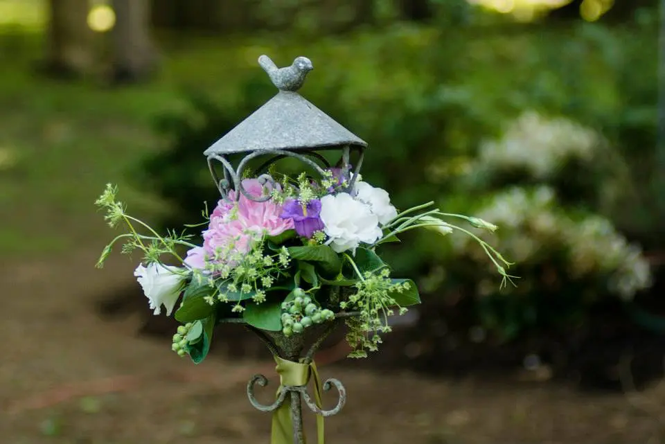 A bird feeder with flowers on top of it.